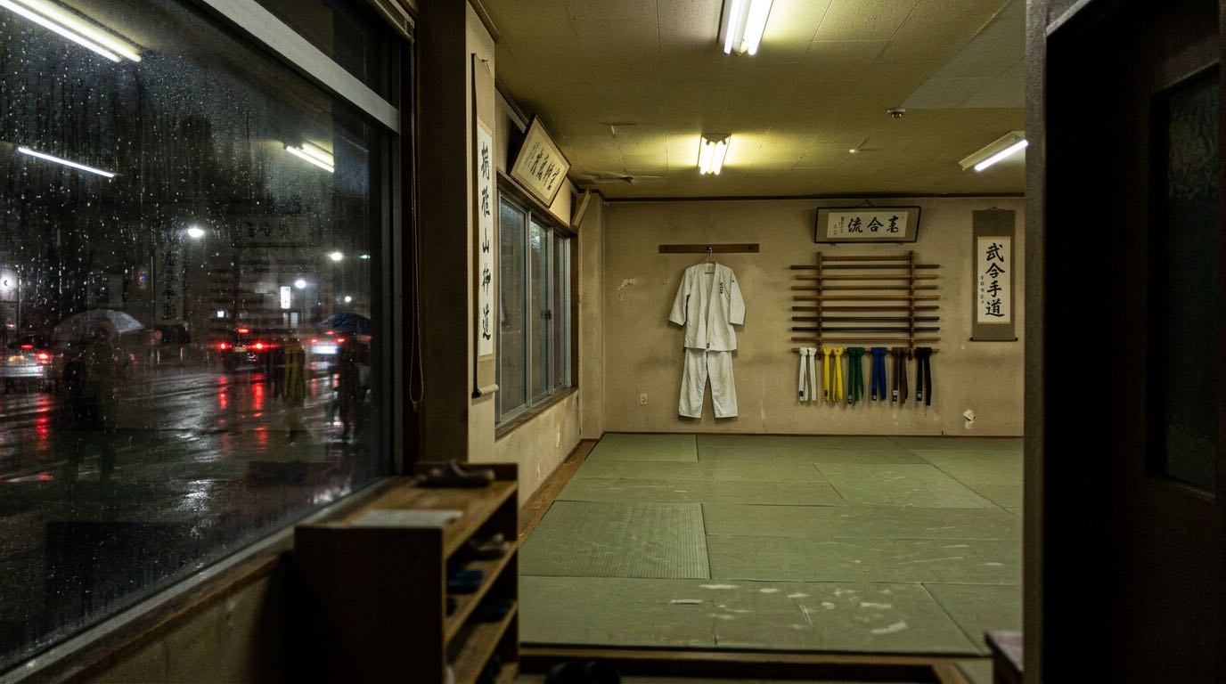 Empty martial arts dojo at night with a rainy street visible through the window