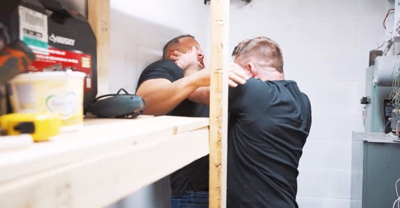 Adam and Andrew drilling a head-and-neck control against a basement workbench