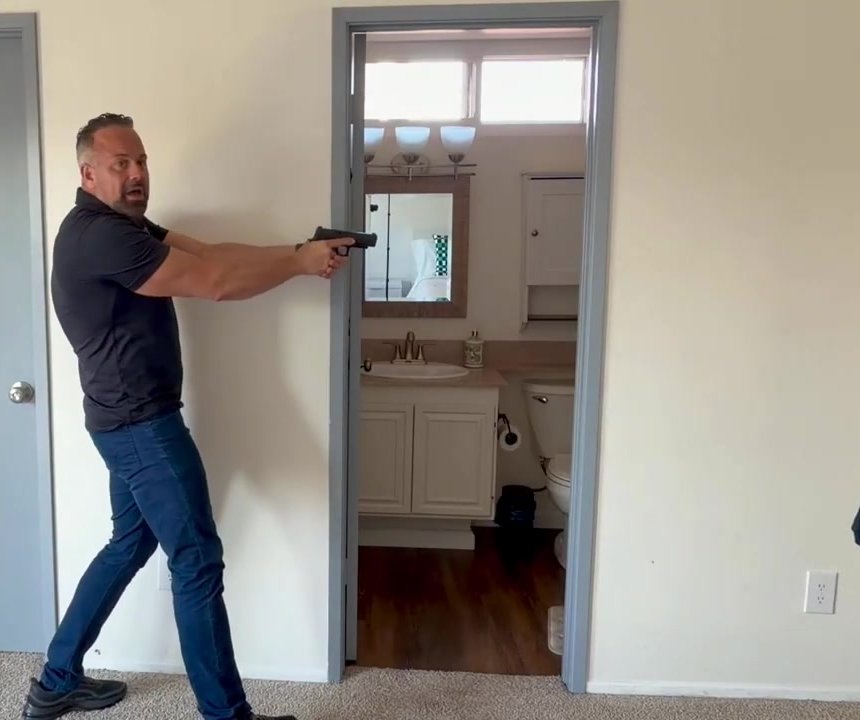 Adam holding a pistol on a doorway threshold during a room-entry lesson