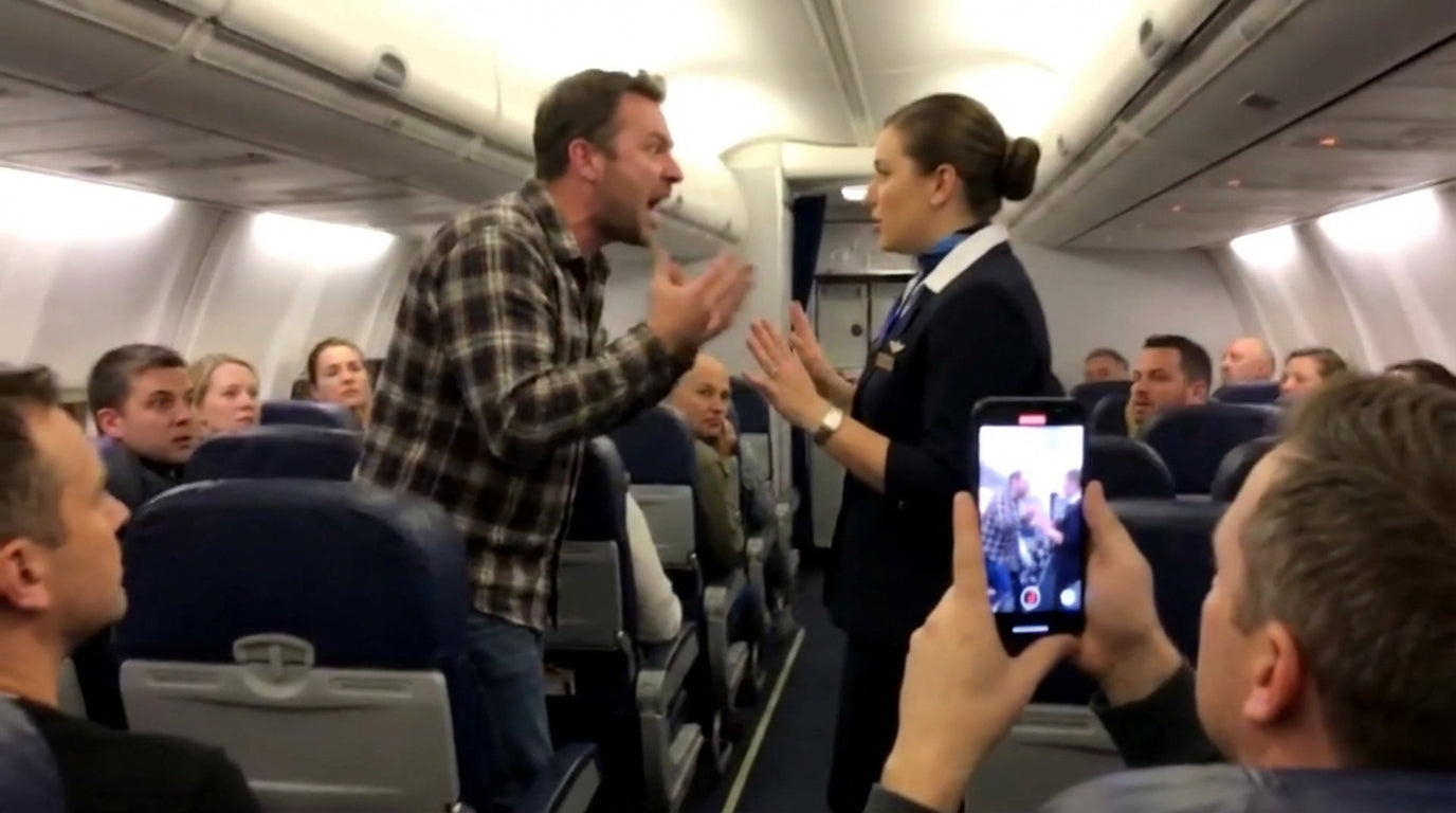 A passenger shouting at a flight attendant in a plane aisle